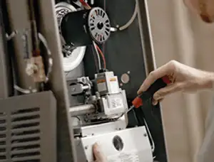 Furnace repair technician inspecting internal components and wiring in Fort Lauderdale, FL