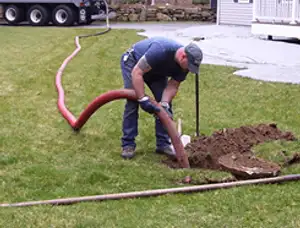 Septic pumping technician servicing a residential septic tank with a vacuum hose in Fort Lauderdale, FL