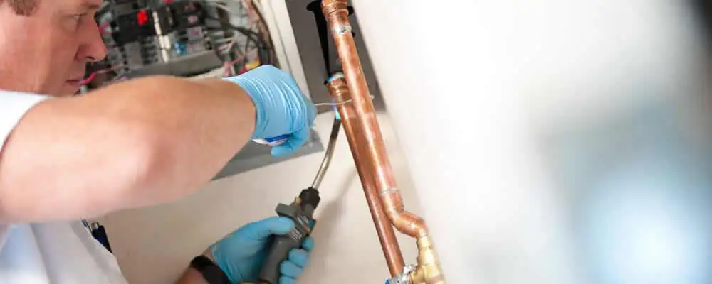 Water heater repair technician testing copper pipe connections and controls in Fort Lauderdale, FL